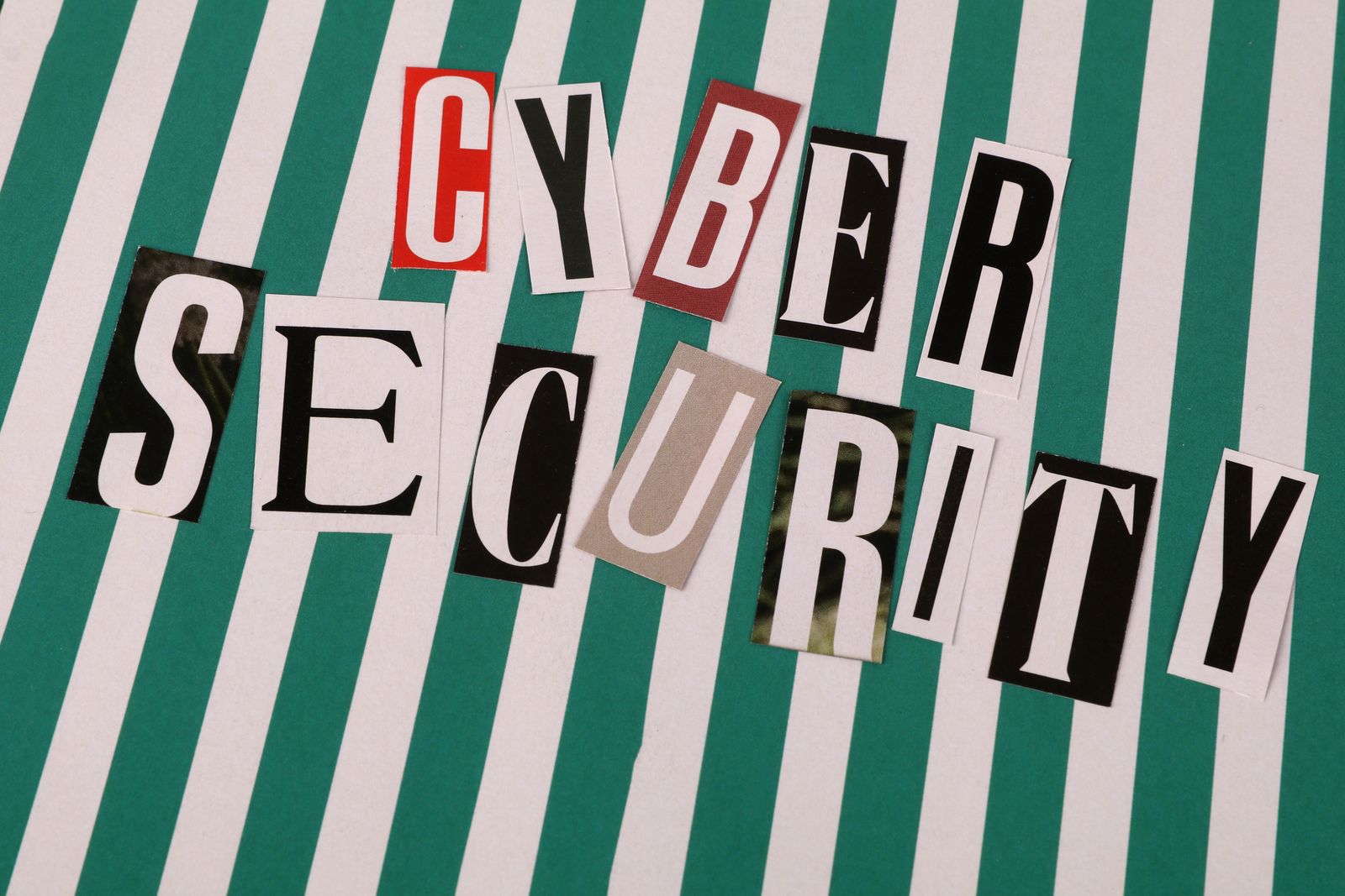 Lettres découpées colorées formant 'Cybersécurité' sur un fond rayé.